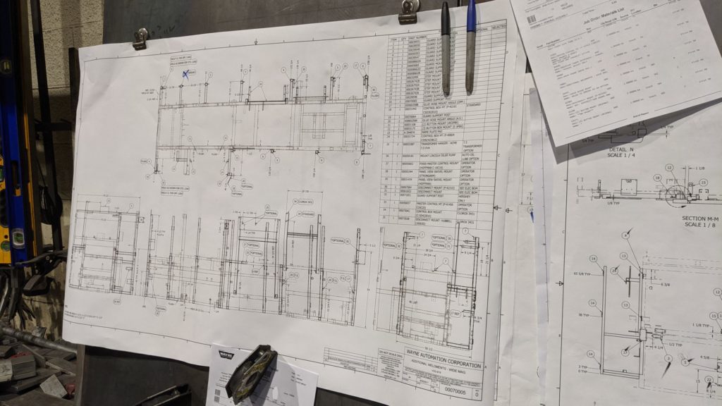 Blueprints on a board that show the outline of a machine and its parts