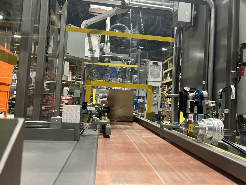 A cardboard box goes through a Wayne Automation machine.