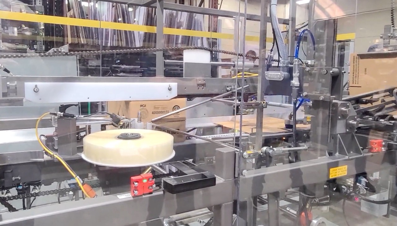Tape roll on an automated case sealing machine, applying tape to cartons on a packaging line.