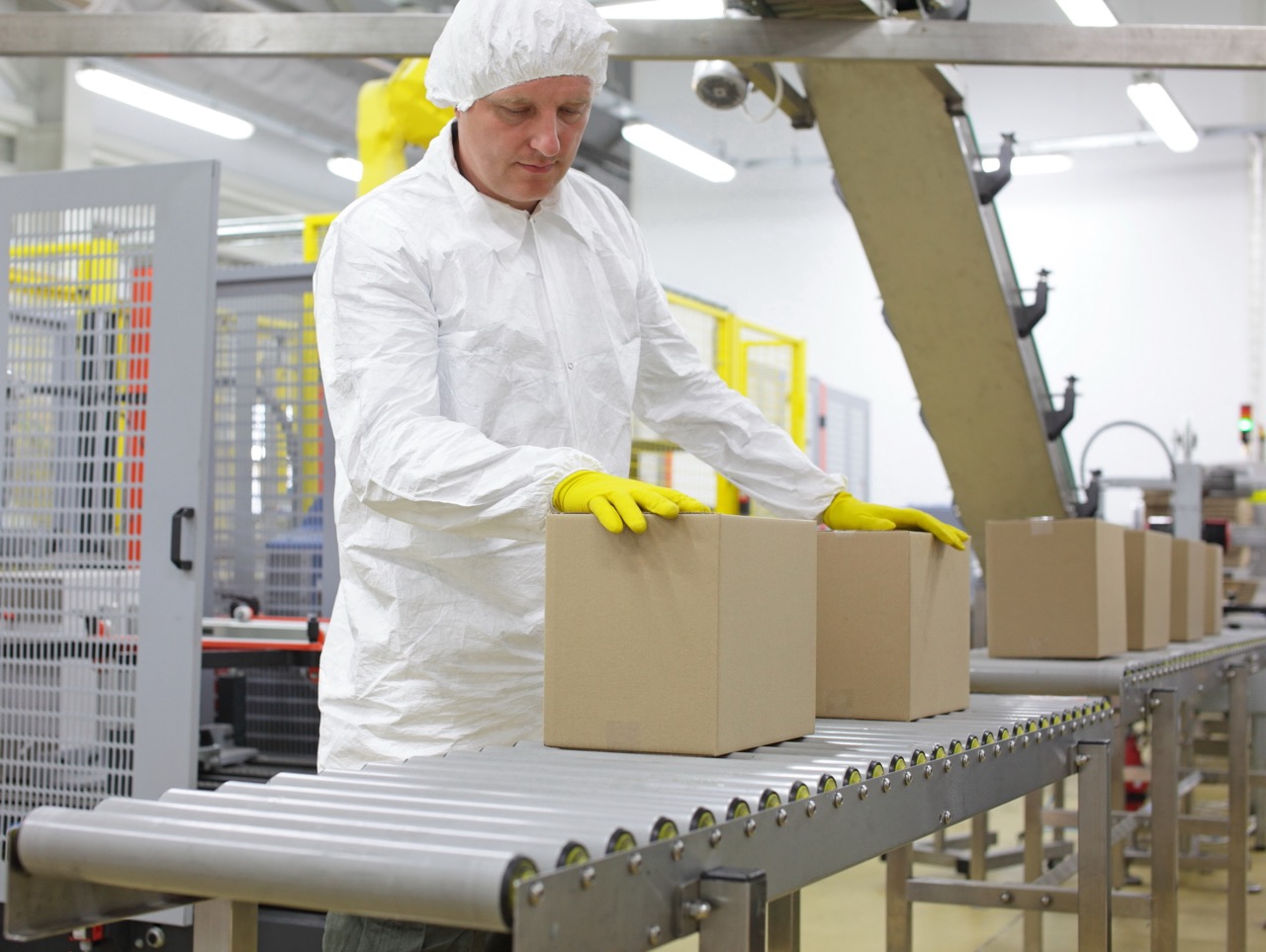 Worker inspects misaligned cartons on conveyor, manual packing slows production and requires extra inspection time.