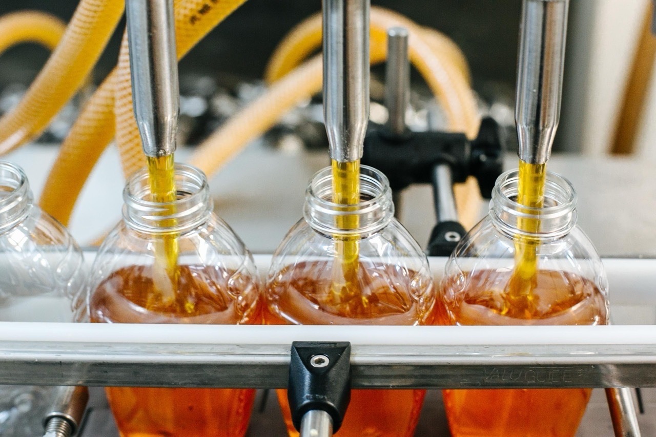 Liquid filler dispensing product into bottles on an automated high-speed packaging line.